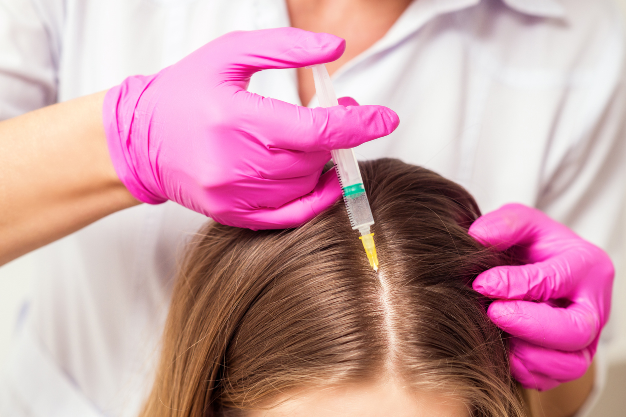 Young woman receiving injection by cosmetologist, close up.